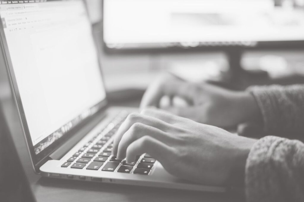 Black-and-white close-up of hands typing on a laptop